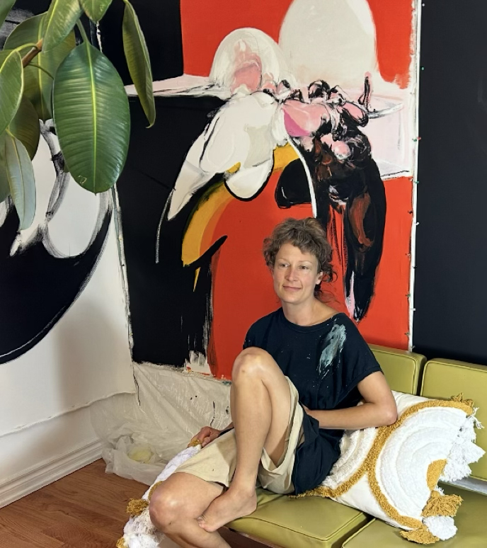 Katie Pretti sitting in her studio with a powerful work currently still in production behind her